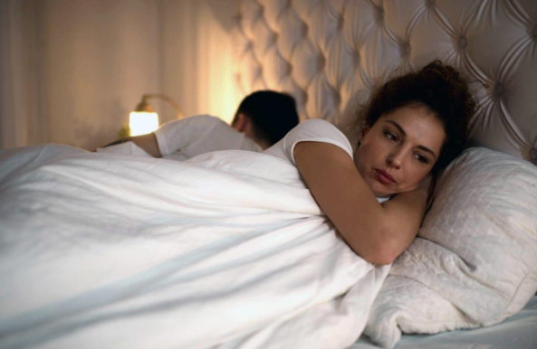 man and woman in bed, separated, unhappy