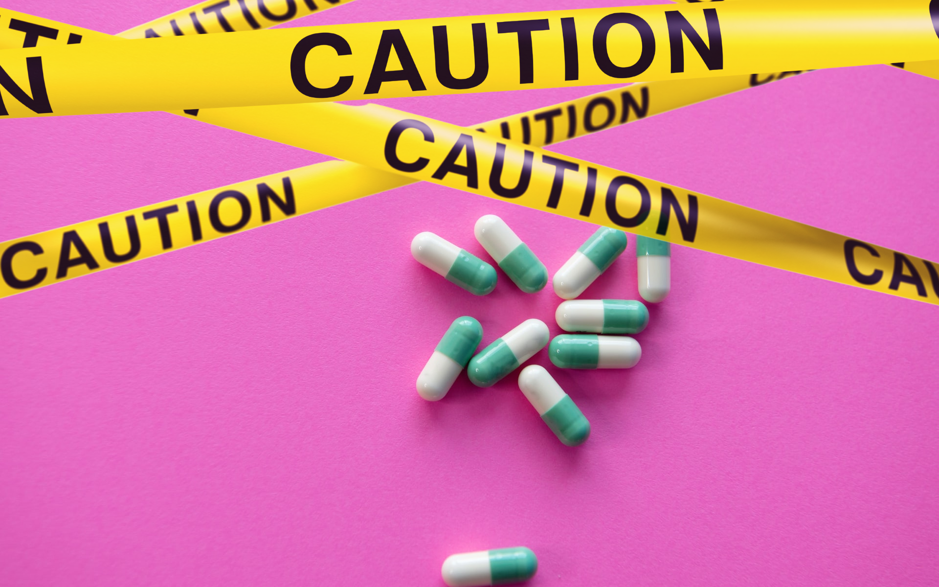 Pills sitting on pink counter surrounded by caution tape.