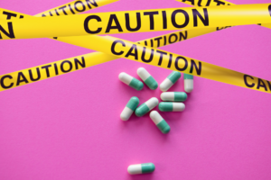 Pills sitting on pink counter surrounded by caution tape.