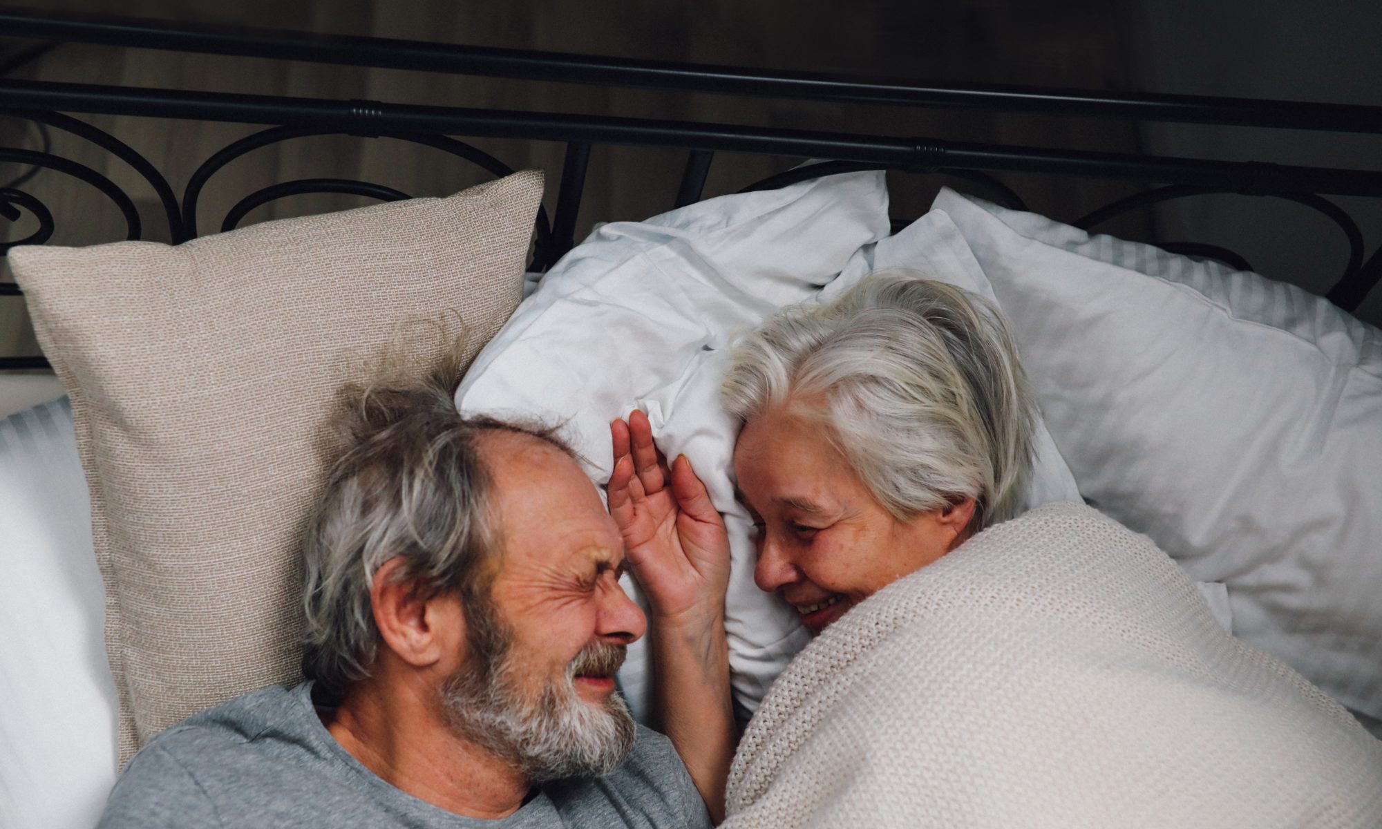 Photograph of older couple cuddling in bed