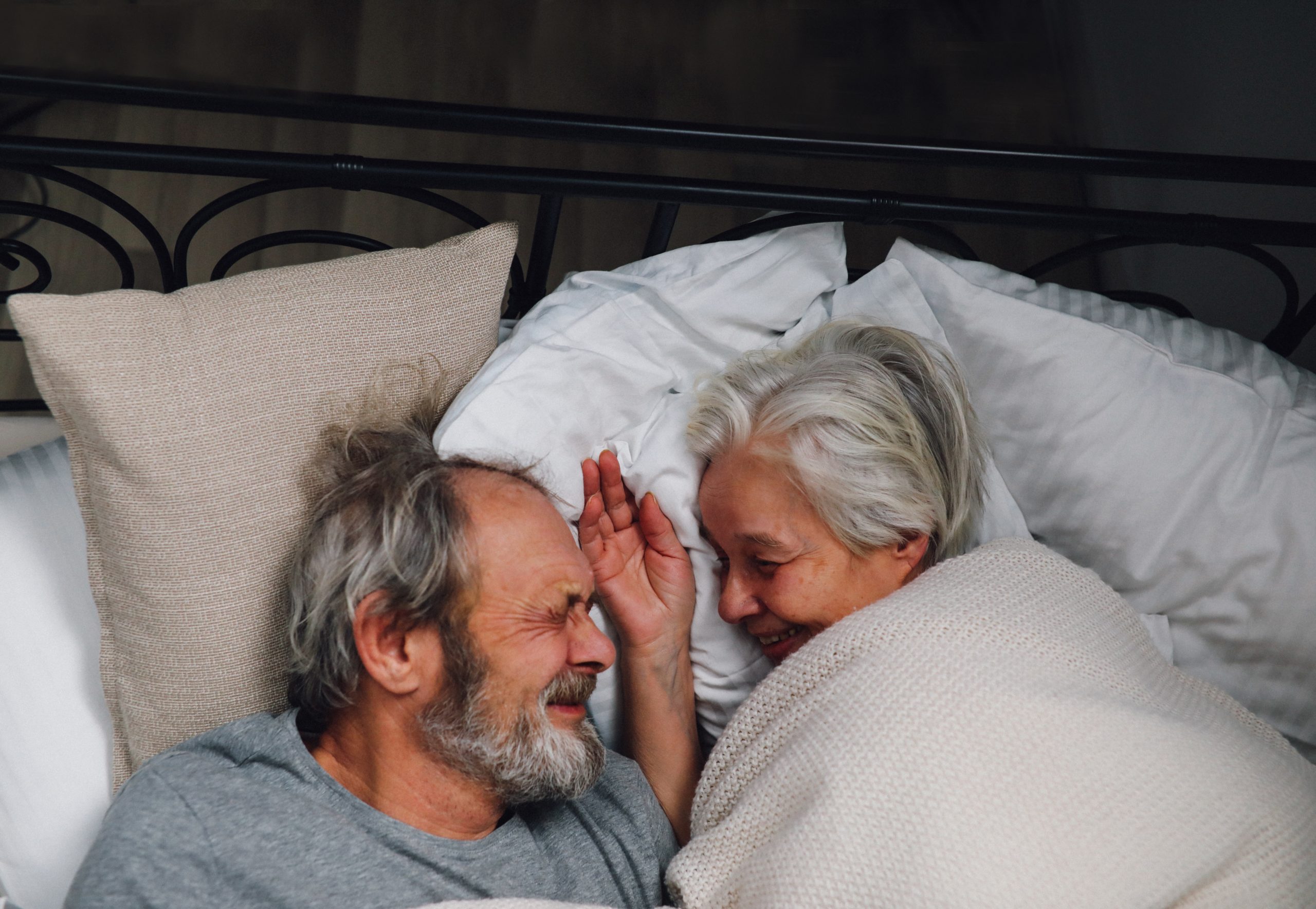 Photograph of older couple cuddling in bed