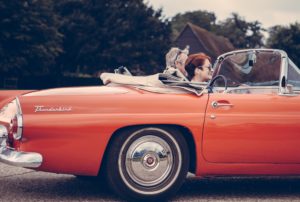 Image of couple riding in an orange Thunderbird convertible