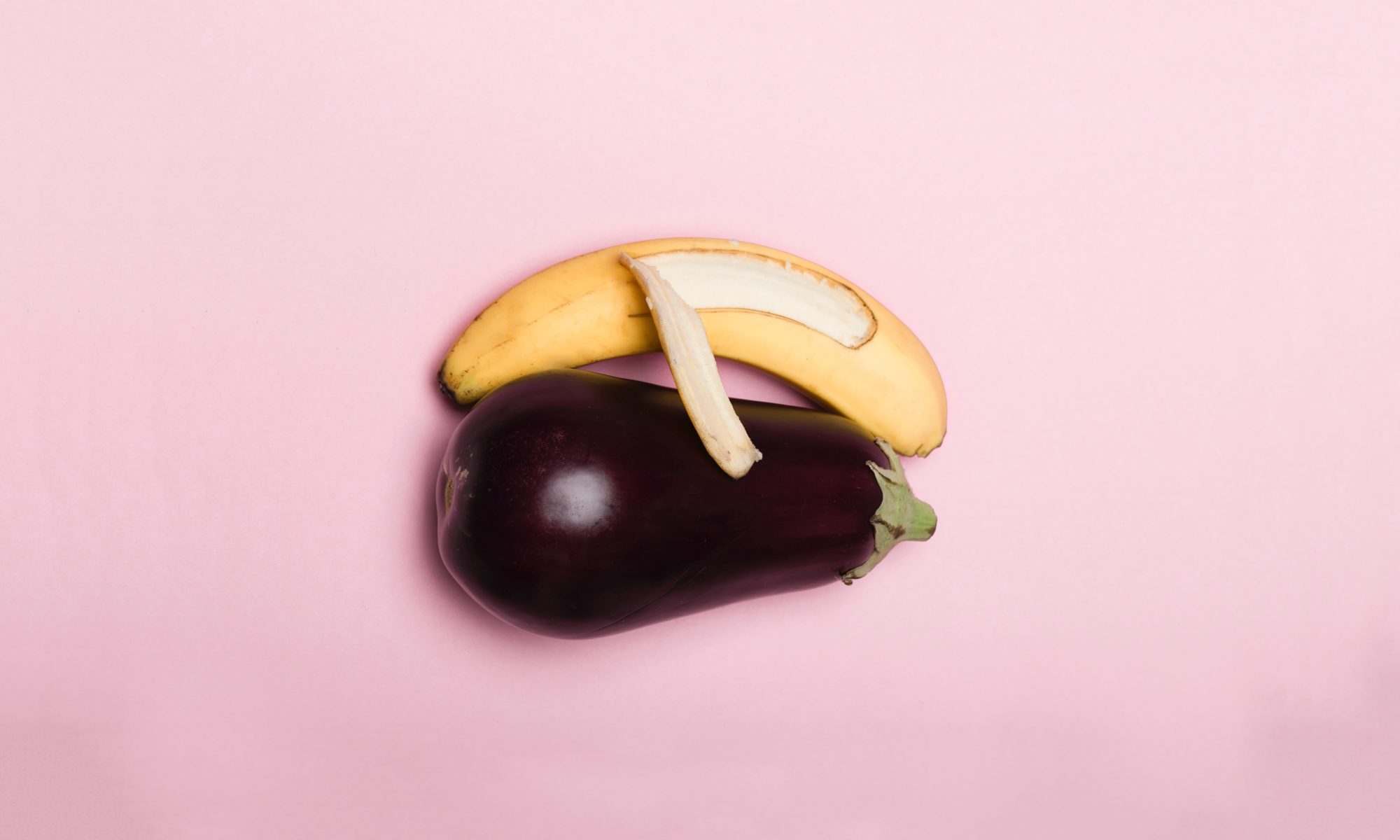 A banana spooning an eggplant with a light pink background.