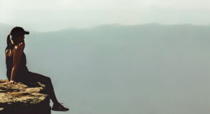 woman sitting on a mountain ledge