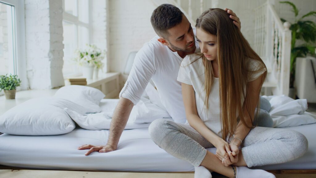 two people sitting on a bed in an intimate moment